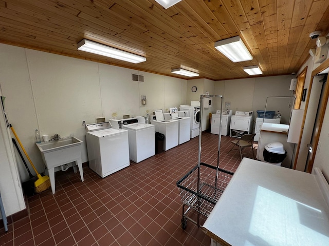 shared laundry with washing machine and dryer, wood ceiling, and dark tile patterned floors