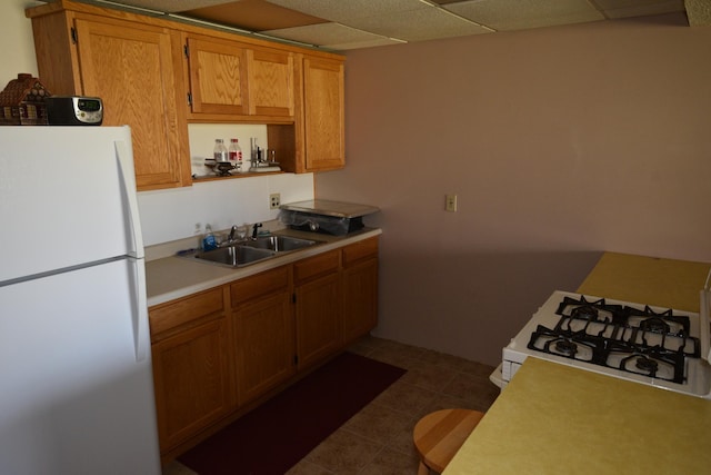 30472 Lightning Pass Unit 1, Turtle Creek Twp, MN 56443 - kitchen featuring brown cabinetry, a sink, light countertops, dark tile patterned flooring, and white appliances