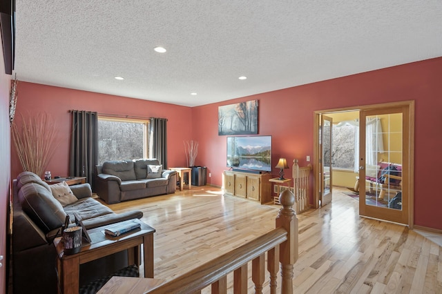 living room with light wood-type flooring, recessed lighting, and a textured ceiling