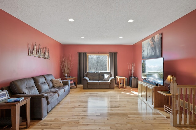 living room with a textured ceiling, recessed lighting, and light wood-style flooring