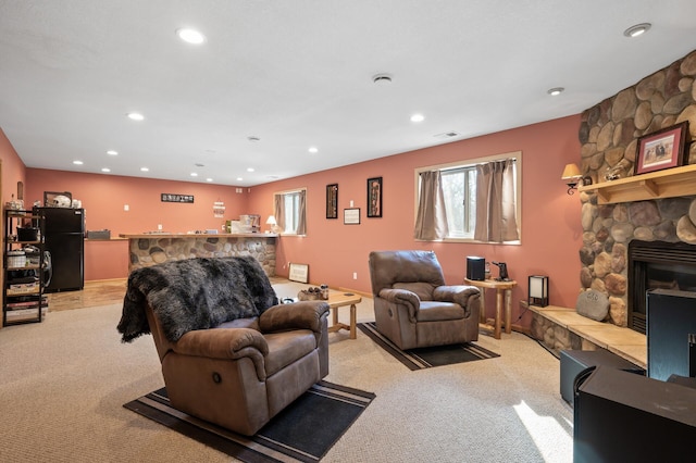living room featuring recessed lighting, a stone fireplace, light carpet, and indoor bar