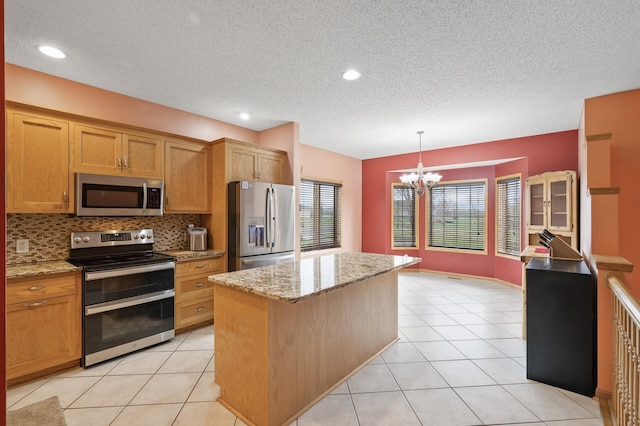 kitchen featuring a center island, a textured ceiling, a notable chandelier, and stainless steel appliances