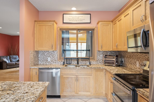 kitchen with a sink, light brown cabinetry, a toaster, and stainless steel appliances