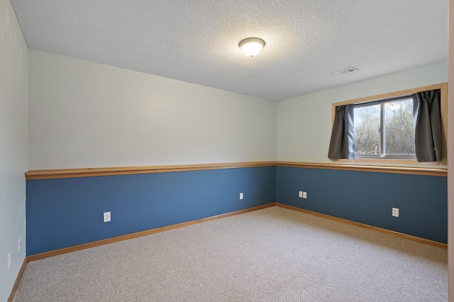 carpeted empty room with a textured ceiling, visible vents, and baseboards