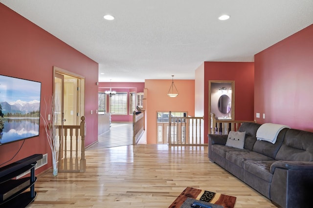 living room with baseboards, recessed lighting, wood finished floors, and a notable chandelier