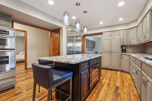 1055 Nelson Dr, Shoreview, MN 55126 - kitchen with stainless steel appliances, tasteful backsplash, light wood-style flooring, a kitchen island, and recessed lighting