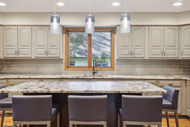 1055 Nelson Dr, Shoreview, MN 55126 - kitchen with a kitchen bar, decorative backsplash, recessed lighting, a sink, and light stone counters