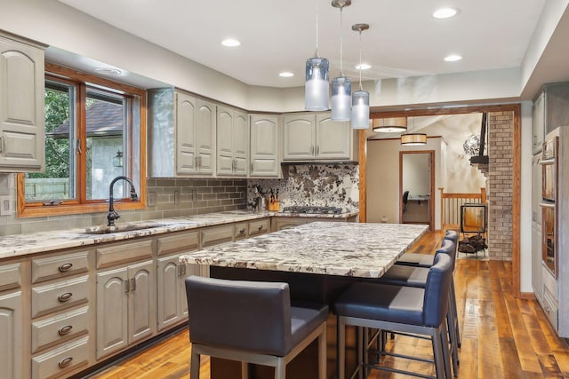 1055 Nelson Dr, Shoreview, MN 55126 - kitchen featuring a sink, light wood-style flooring, decorative backsplash, light stone countertops, and decorative light fixtures