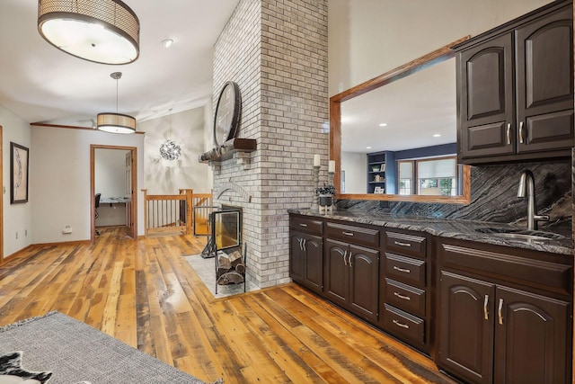 1055 Nelson Dr, Shoreview, MN 55126 - kitchen featuring a sink, dark brown cabinetry, light wood finished floors, and tasteful backsplash
