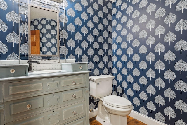1055 Nelson Dr, Shoreview, MN 55126 - bathroom featuring wallpapered walls, baseboards, toilet, vanity, and wood finished floors