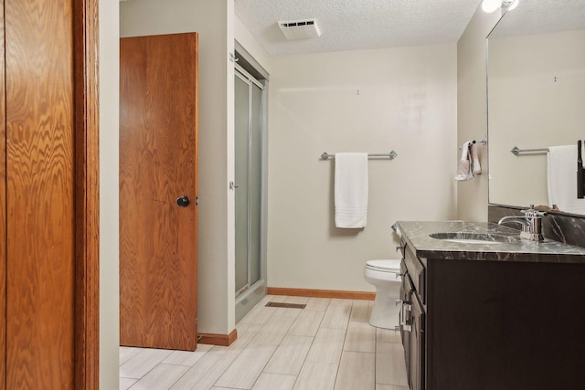 1055 Nelson Dr, Shoreview, MN 55126 - bathroom featuring vanity, toilet, a shower with door, a textured ceiling, and baseboards