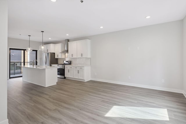 kitchen featuring light wood-style floors, baseboards, wall chimney exhaust hood, white cabinetry, and stainless steel appliances