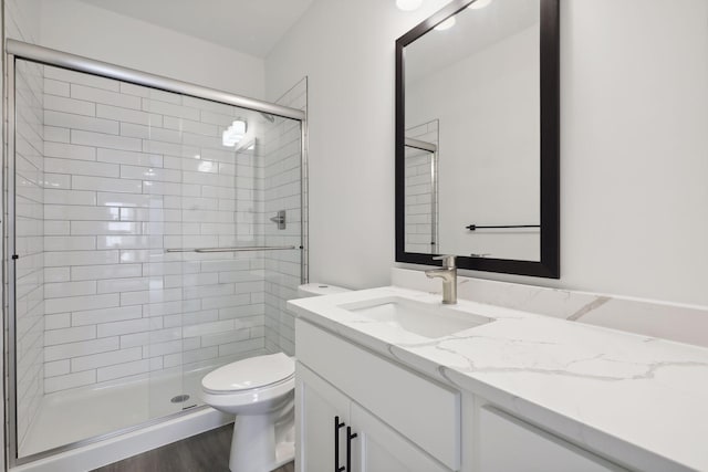full bathroom featuring vanity, a stall shower, toilet, and wood finished floors