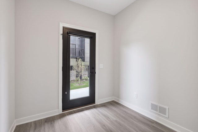 doorway featuring baseboards, wood finished floors, and visible vents