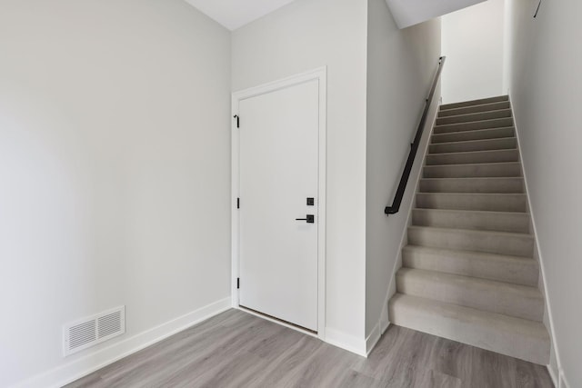 stairway with baseboards, wood finished floors, and visible vents