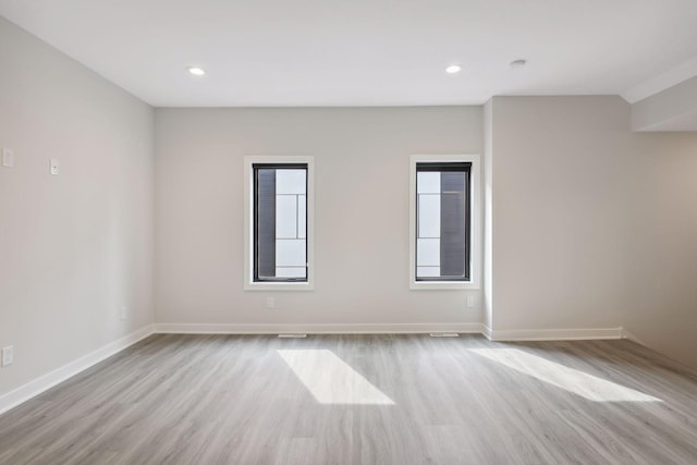 empty room featuring baseboards, plenty of natural light, recessed lighting, and wood finished floors