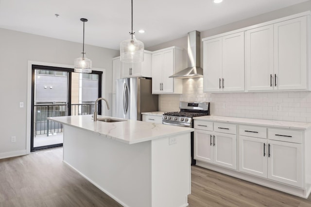 kitchen with wall chimney range hood, light wood-type flooring, tasteful backsplash, a sink, and appliances with stainless steel finishes