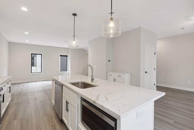 kitchen featuring hanging light fixtures, a sink, light wood finished floors, open floor plan, and stainless steel appliances