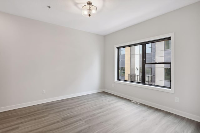 empty room featuring baseboards, visible vents, and wood finished floors