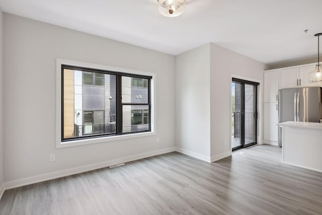 unfurnished living room with a healthy amount of sunlight, baseboards, and light wood-style floors