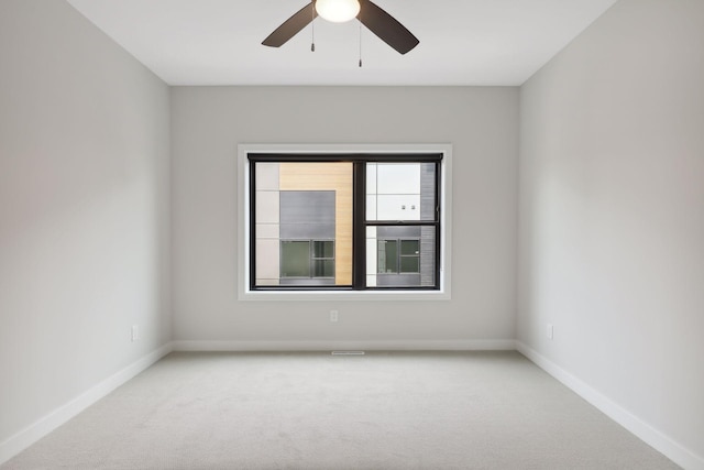 unfurnished room featuring a ceiling fan, baseboards, and light colored carpet