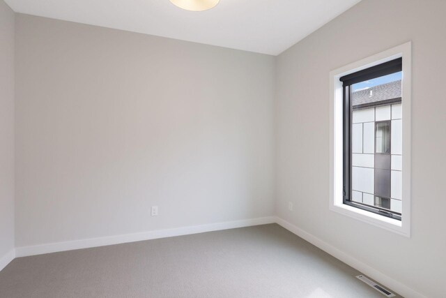 carpeted spare room featuring baseboards and visible vents