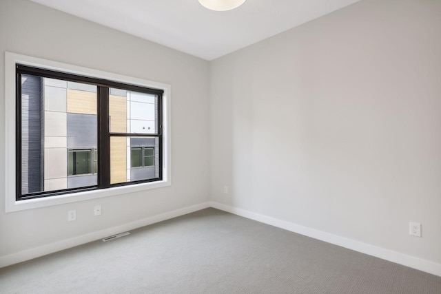 spare room featuring baseboards, visible vents, and carpet