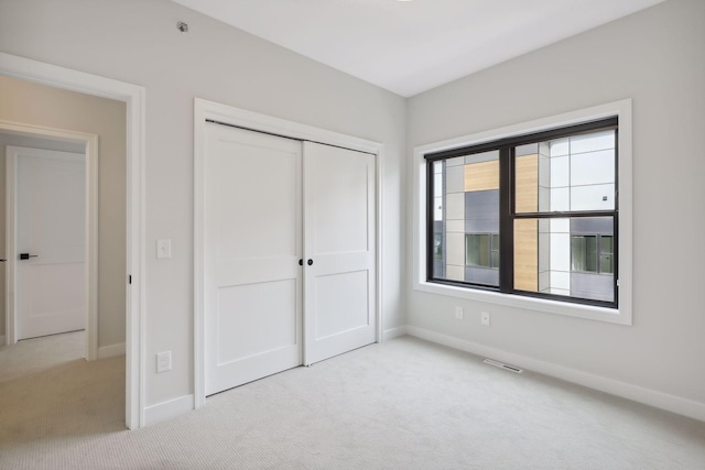unfurnished bedroom with baseboards, carpet, a closet, and visible vents