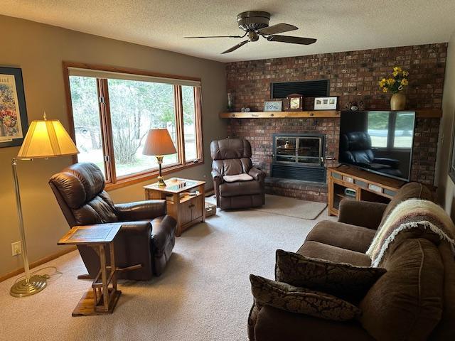 9700 Aspen Ave NW, Bemidji, MN 56601 - living room featuring carpet floors, a ceiling fan, a textured ceiling, and a fireplace