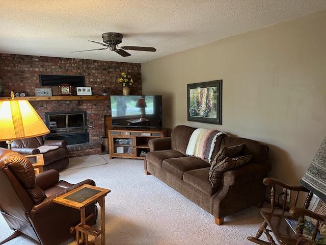 9700 Aspen Ave NW, Bemidji, MN 56601 - carpeted living room with ceiling fan, a fireplace, and a textured ceiling