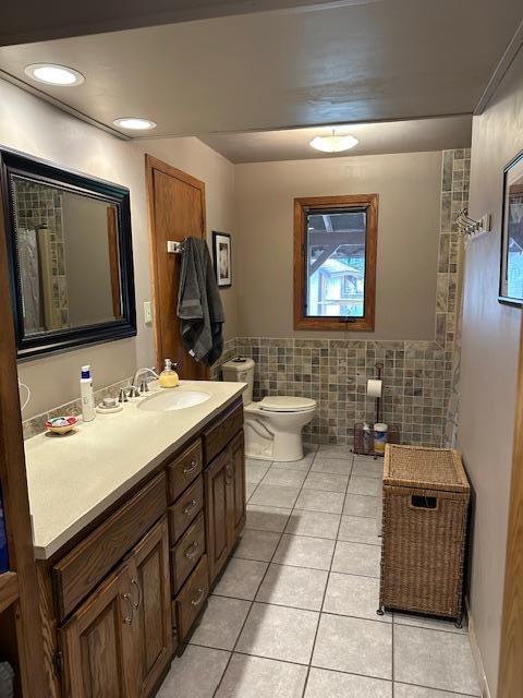 9700 Aspen Ave NW, Bemidji, MN 56601 - full bath with tile patterned floors, tile walls, vanity, and a wainscoted wall
