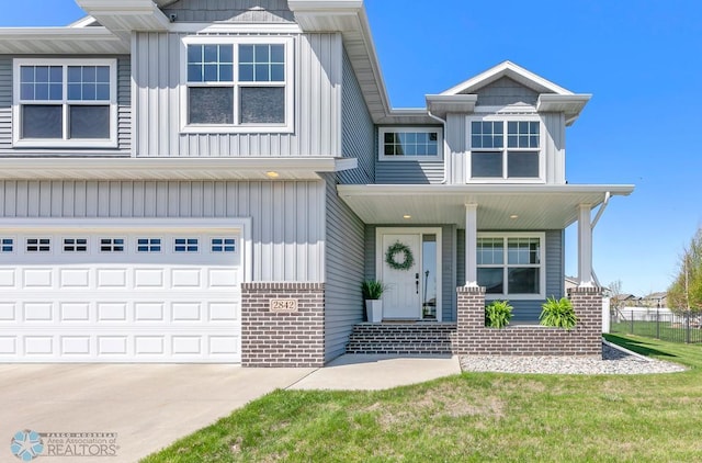 view of front of home featuring a porch, brick siding, an attached garage, and board and batten siding