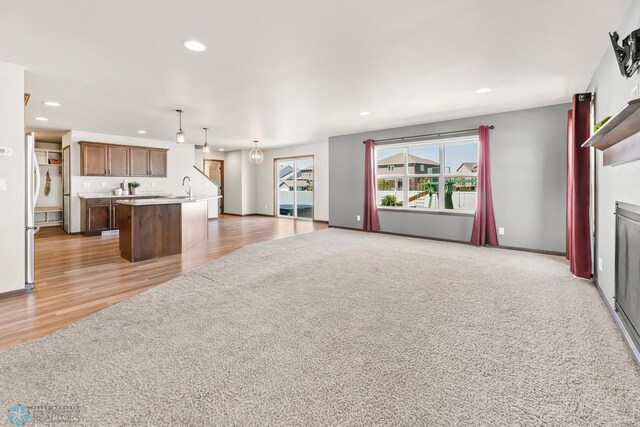 unfurnished living room featuring recessed lighting, light wood-type flooring, and a sink