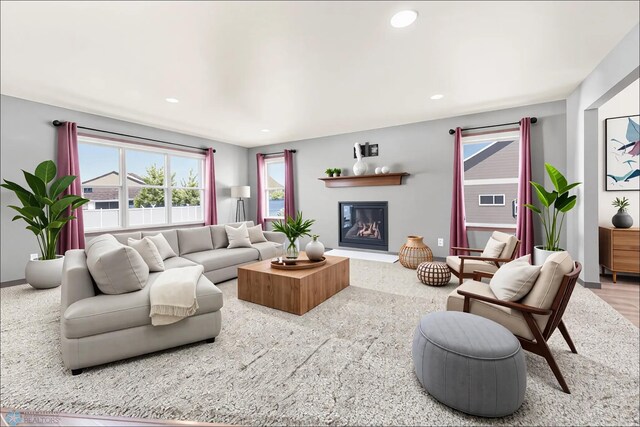 living area with a glass covered fireplace, recessed lighting, and baseboards