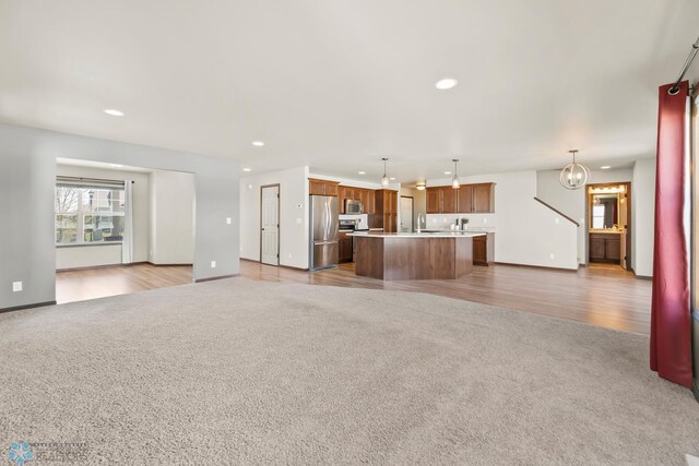 unfurnished living room featuring carpet, recessed lighting, baseboards, and a chandelier