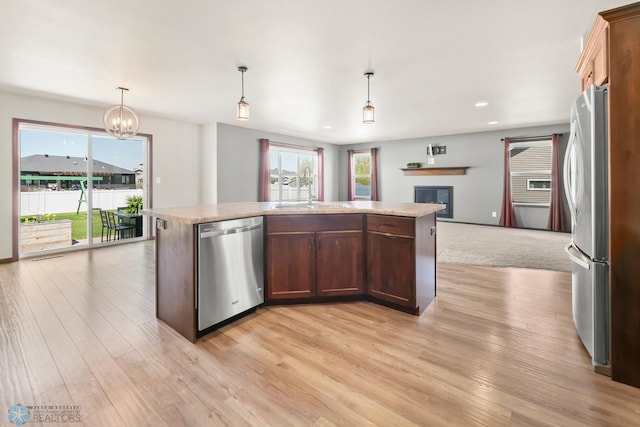 kitchen with stainless steel appliances, a sink, open floor plan, light wood-type flooring, and light countertops