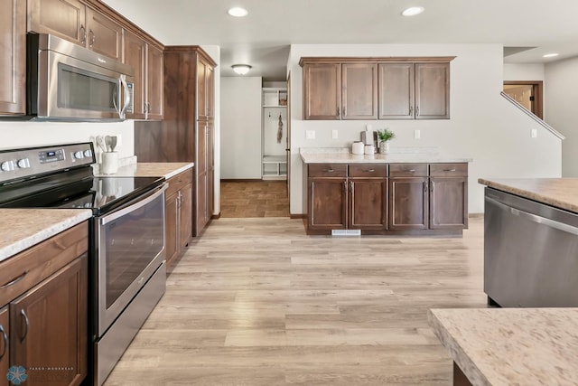 kitchen featuring stainless steel appliances, light wood finished floors, light countertops, and recessed lighting