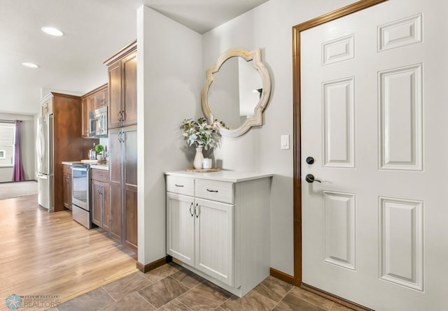 kitchen featuring stainless steel appliances, light countertops, baseboards, and recessed lighting