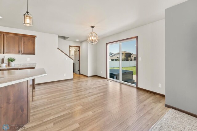 unfurnished living room featuring baseboards, light wood-style floors, a chandelier, and recessed lighting