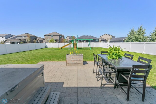 view of patio featuring a playground, outdoor dining space, a residential view, and a hot tub