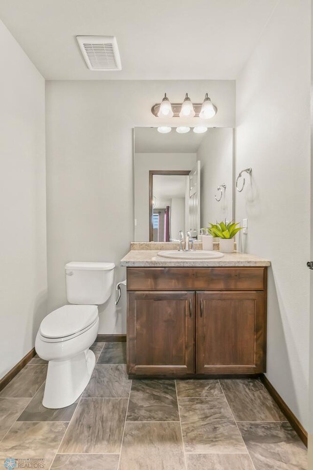 half bathroom with toilet, baseboards, and vanity