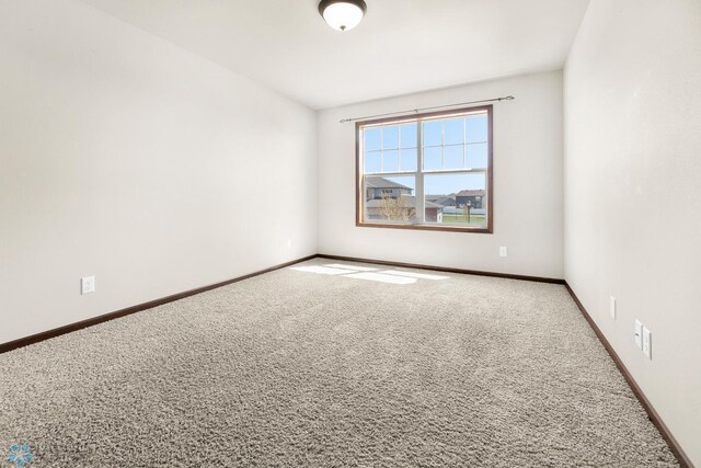 unfurnished room featuring carpet and baseboards