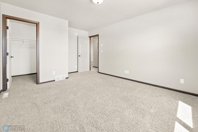 unfurnished bedroom featuring baseboards, carpet, a walk in closet, and a closet