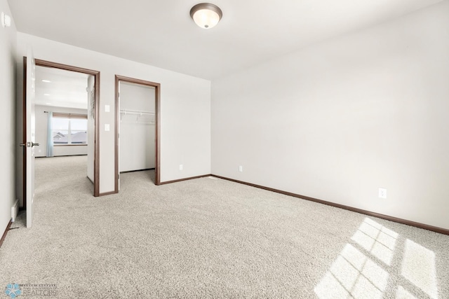 unfurnished bedroom featuring light carpet, baseboards, a closet, and a walk in closet