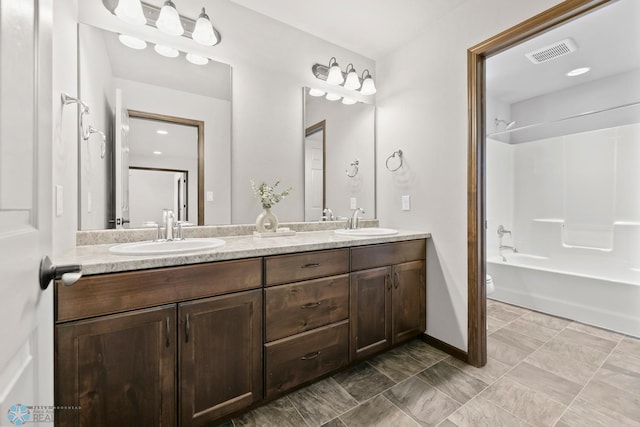 bathroom featuring double vanity, toilet, shower / washtub combination, and baseboards