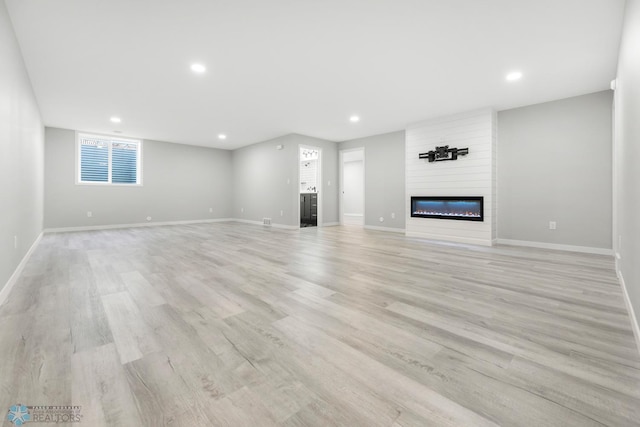 unfurnished living room featuring recessed lighting, a fireplace, baseboards, and light wood-type flooring