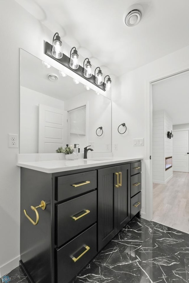 bathroom with vanity, baseboards, and marble look tile flooring