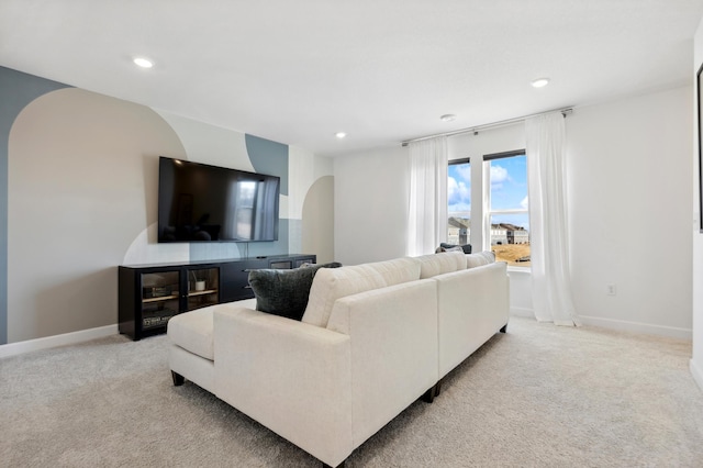 living room featuring arched walkways, light carpet, recessed lighting, and baseboards
