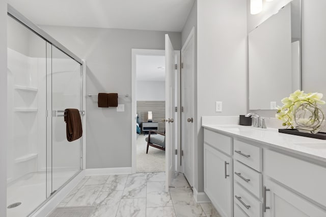 ensuite bathroom with marble look tiles, a stall shower, vanity, and baseboards