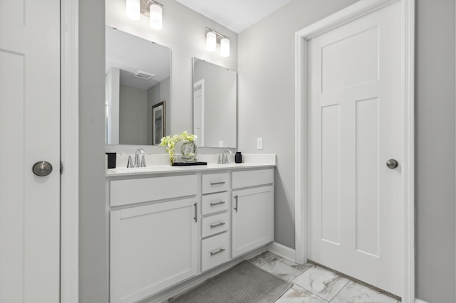 bathroom with marble finish flooring, double vanity, and baseboards